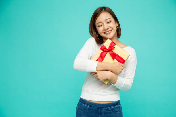 happy beautiful asian woman smile with gold gift box isolated on green background. teenage girls in love, receiving gifts from lovers. new year or christmas concept - suitor imagens e fotografias de stock