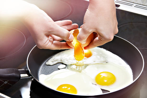 istock Woman breaks egg in pan 1217315125