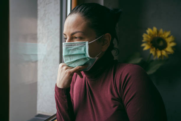 istock Young Woman is looking out the window during self isolation quarantine. 1217318953