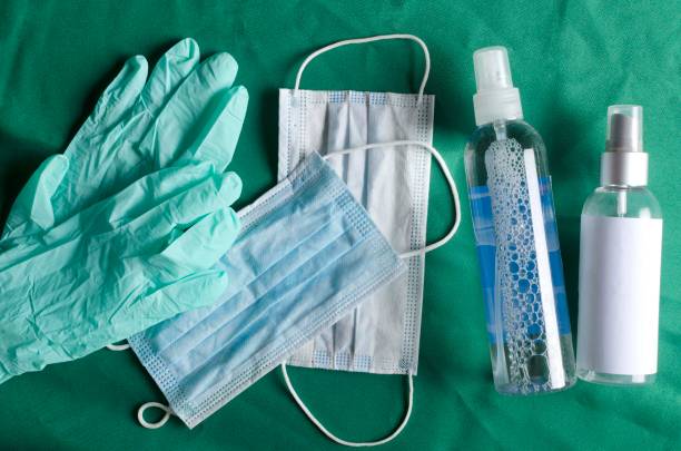 dispositivi di protezione di base sul tavolo operatorio verde. bottiglie di sapone per le mani e disinfettante, guanti medici e maschere - equipments foto e immagini stock