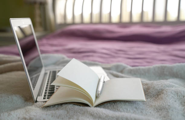 istock Notepad and computer laptop on top of bed. 1217326338