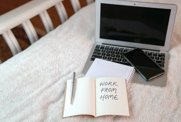 istock Computer laptop with cellphone and notepad on top of bed. 1217326689