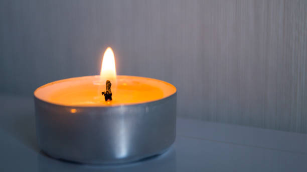 istock One small burning candle on a light background. Comfort, homely romantic atmosphere. 1217326810