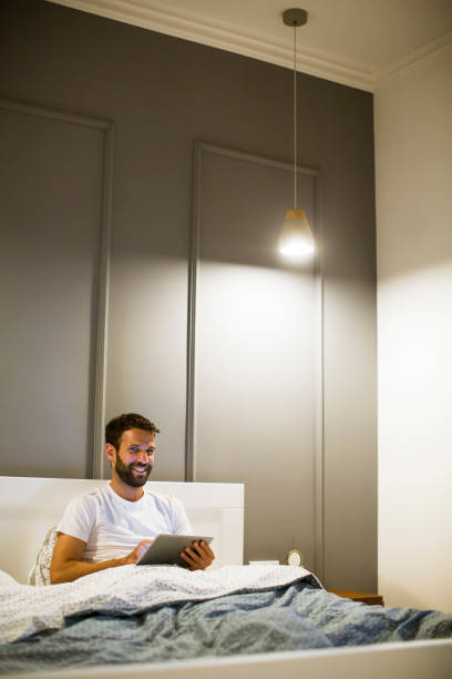 istock Young man reading book in the bed 1217327427
