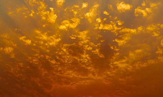 Beautiful sunset sky. Golden sunset sky with beautiful pattern of clouds. Orange, yellow, and red clouds in the evening. Freedom and calm background. Beauty in nature. Powerful and spiritual scene.
