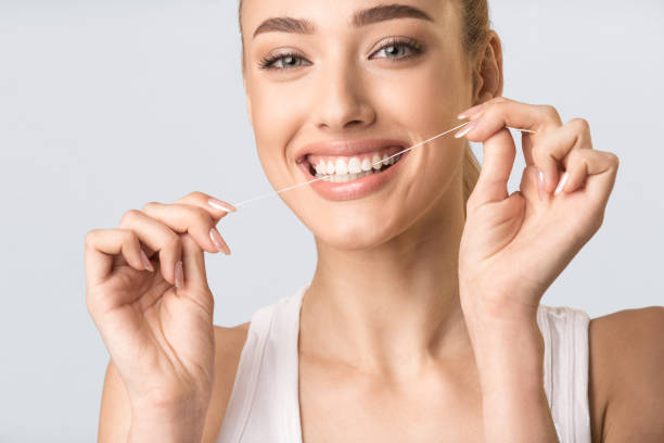 istock Girl Using Floss Cleaning Teeth Standing Over Gray Background, Studio 1217330062