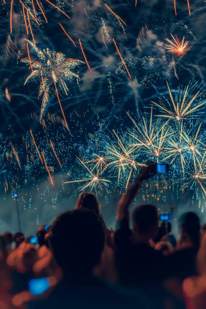 abstracto borroso multitud irreconocible de jóvenes de vuelta a nosotros en fuegos artificiales de vacaciones, cielo pintoresco en chispas de colores - unrecognizable person flash fotografías e imágenes de stock