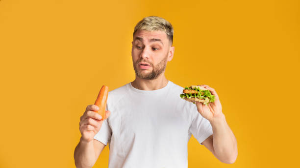 istock Ridiculous man chooses vegetables or fast food 1217331156