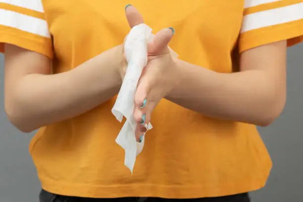 Girl rubs her hands with an antibacterial sanitary napkin on a gray background