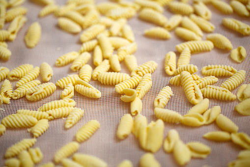 Close-up of freshly made cavatelli pasta on a fabric. Handmade pasta on kitchen counter.