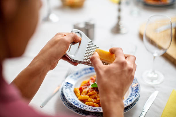 Man garnishing pasta with cheese at cooking class