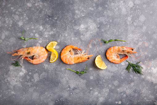 Boiled Vannamei shrimps, whiteleg shrimp, Pacific white shrimp or king prawn on gray background. Top view, copy space, food background.