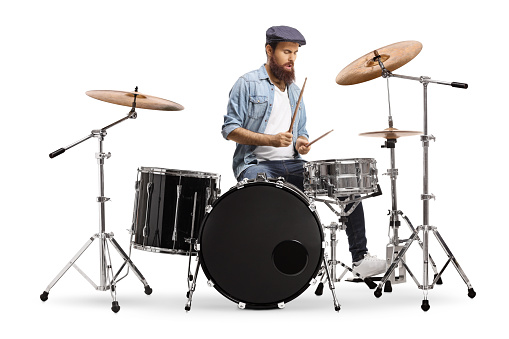 Casual bearded guy mucician playing a drum set isolated on white background