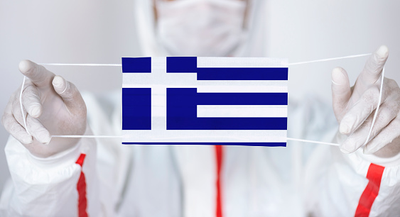Healthcare personnel is holding Greek Flag shaped surgical mask.