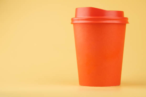 istock Coffee cup red with a red lid on yellow background. Coffee to go concept 1217341987