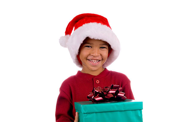Cute Caucasian blond toddler boy is holding Christmas present and looking at camera. He is wearing Christmas sweater, photo booth eyeglasses and is happy. White background.