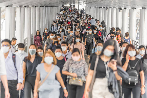 Crowd of unrecognizable business people wearing surgical mask for prevent coronavirus Outbreak Bangkok, Thailand - Mar 2020 : Crowd of unrecognizable business people wearing surgical mask for prevent coronavirus Outbreak in rush hour working day on March 18, 2020 at Bangkok transportation bts skytrain stock pictures, royalty-free photos & images