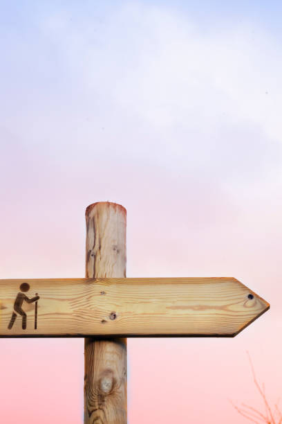 Footpath sign post, cloudscape sunset background. Footpath sign post, cloudscape sunset background, hiking pole with hiking symbol figurine. Copy space available. hiking trail markers stock pictures, royalty-free photos & images