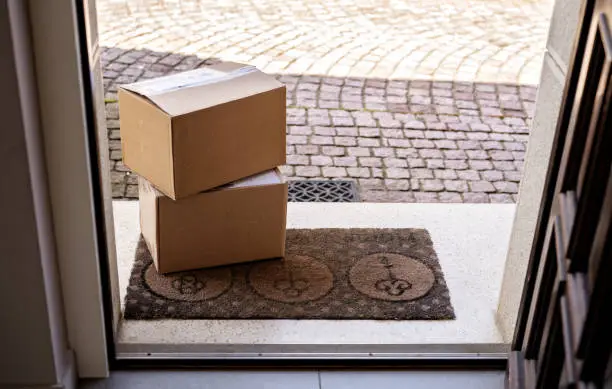 Contacless delivery service during quarantine. Two carton boxes delivered and left oudside ar entrance door. View from inside through open door.