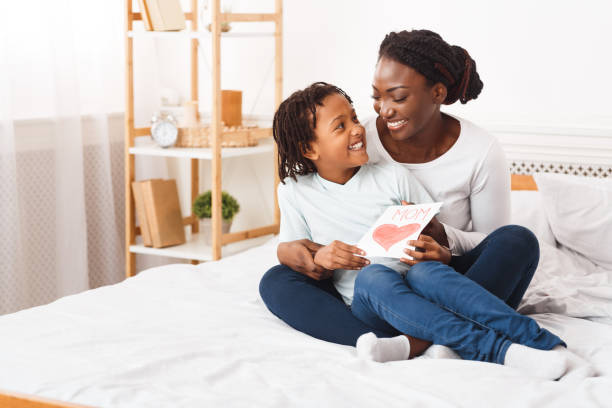 istock Afro kid congratulating her mom sitting on the bed 1217347272