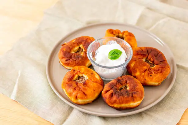 Photo of Meat pies served with sour cream sauce. The traditional Kazakh, Tatar and Bashkir food - belyashi.