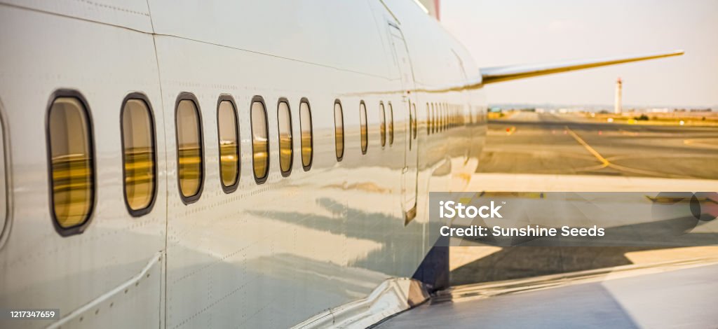 Airplane windows of a jumbo jet parked on the tarmac at an airport Airplane windows of a jumbo jet parked on the tarmac at an airport on a sunny day Boeing 747-400 Stock Photo