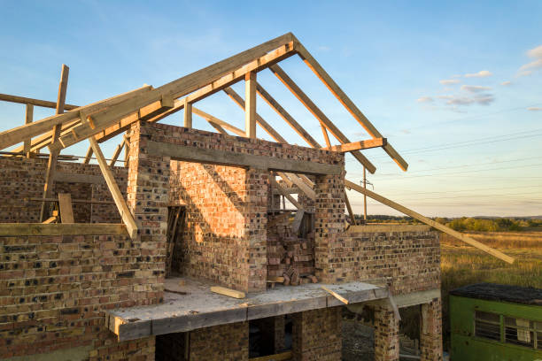 istock Private residential house with wooden roof frame structure under construction. Unfinished brick building under development. 1217347830