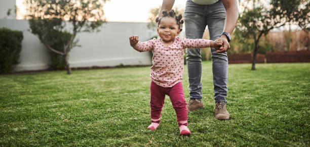Look who's walking! Shot of an adorable baby girl having fun with her dad in their backyard offspring photos stock pictures, royalty-free photos & images