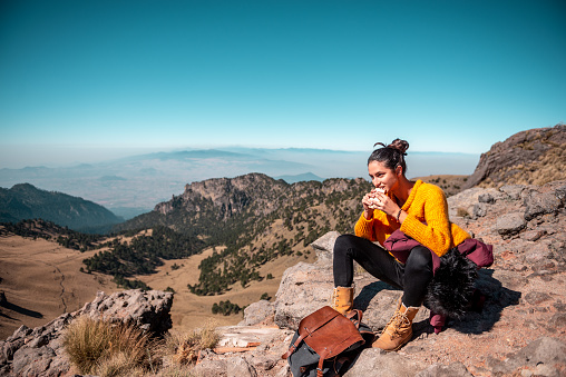 Tired Latin woman making a launch break. She is hiking at Popocatepetl volcano in Mexico