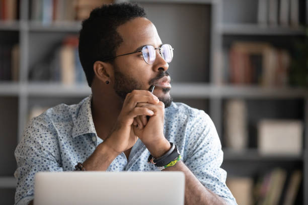 istock Pensive biracial man lost in thoughts dreaming at workplace 1217350972
