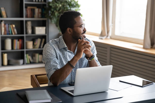 istock Happy biracial man look in distance dreaming at workplace 1217350977