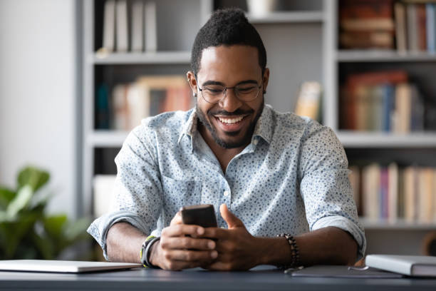 istock Smiling african American man laugh using smartphone gadget 1217350984