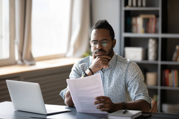 istock Pensive biracial man reading paper document at workplace 1217350989