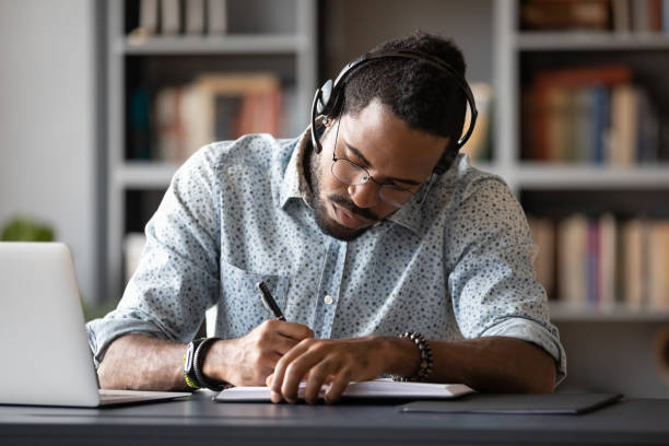 istock Focused biracial man in headphones make notes studying 1217350997