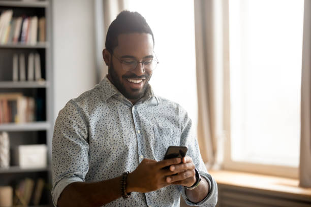 istock Smiling biracial man have fun texting on cell 1217351071