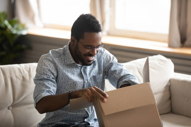 istock Excited biracial man unpack internet delivery order package 1217351085