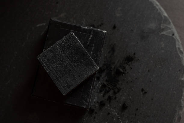 istock black carbon charcoal soap on a black stone background 1217352138
