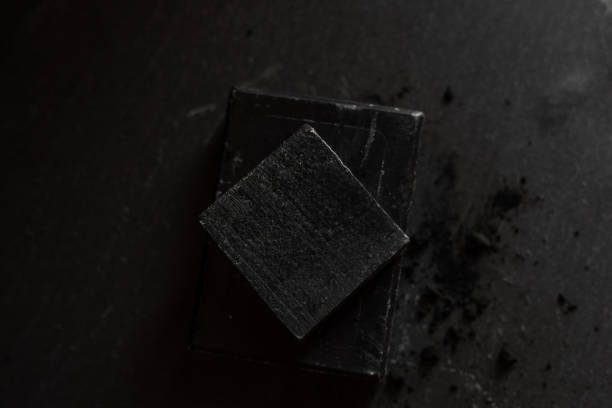 istock black carbon charcoal soap on a black stone background 1217353175