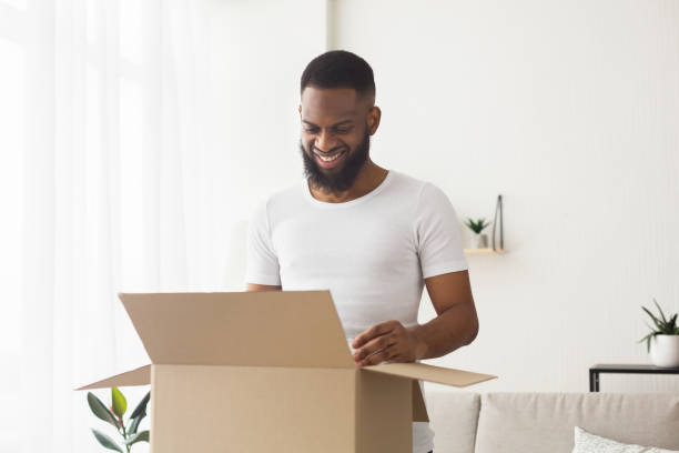 istock Glad african american millennial man opens box 1217353355