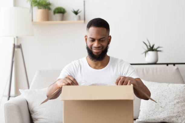 istock Glad african american millennial guy opens big box 1217353672