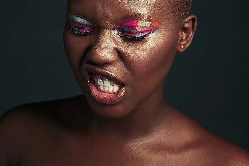 Cropped shot of a beautiful woman wearing colorful eyeshadow while posing against a grey background