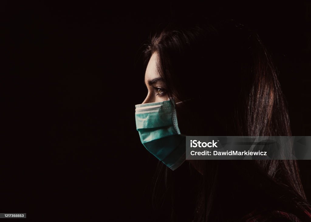 Beautiful woman in a blue mask Portrait in profile of a beautiful woman in a mask on a black background Protective Face Mask Stock Photo