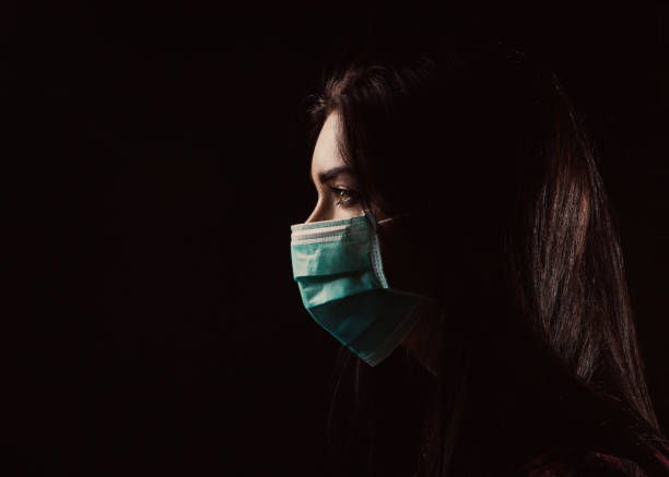 Beautiful woman in a blue mask Portrait in profile of a beautiful woman in a mask on a black background avian flu virus photos stock pictures, royalty-free photos & images