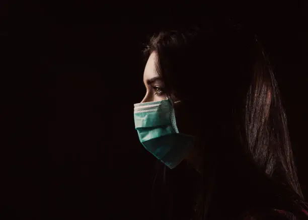 Portrait in profile of a beautiful woman in a mask on a black background