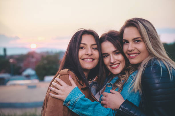 Three beautiful caucasian joyful teenage girls having fun outdoor, in public park.