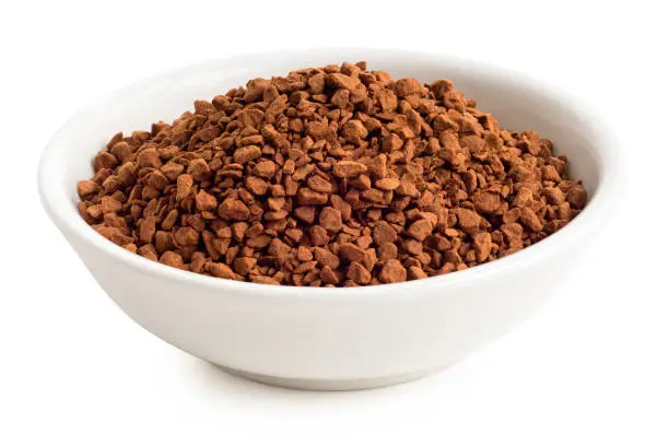 Dry instant coffee in a white ceramic dish isolated on white.