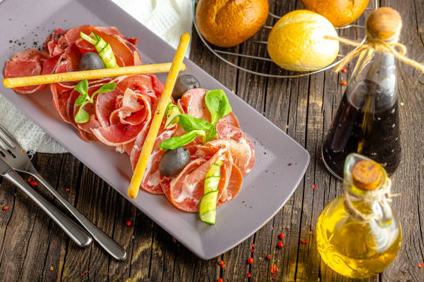 istock rustic wooden background, top and side, cold cuts, bacon and beef appetizer, fresh herbs, bread sticks and olives 1217359329