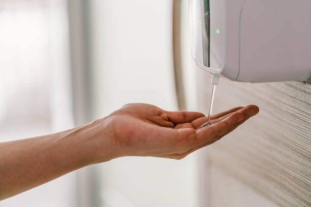 Closeup Asian woman hand using wash hand sanitizer gel dispenser automatic machine stock photo
