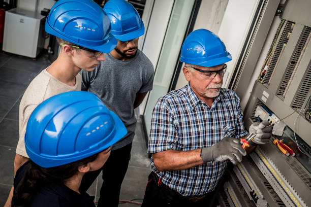 istock Senior electrician cutting a wire in front of his students 1217362920