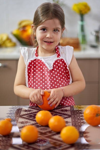 istock Little girl peeling oranges 1217363229